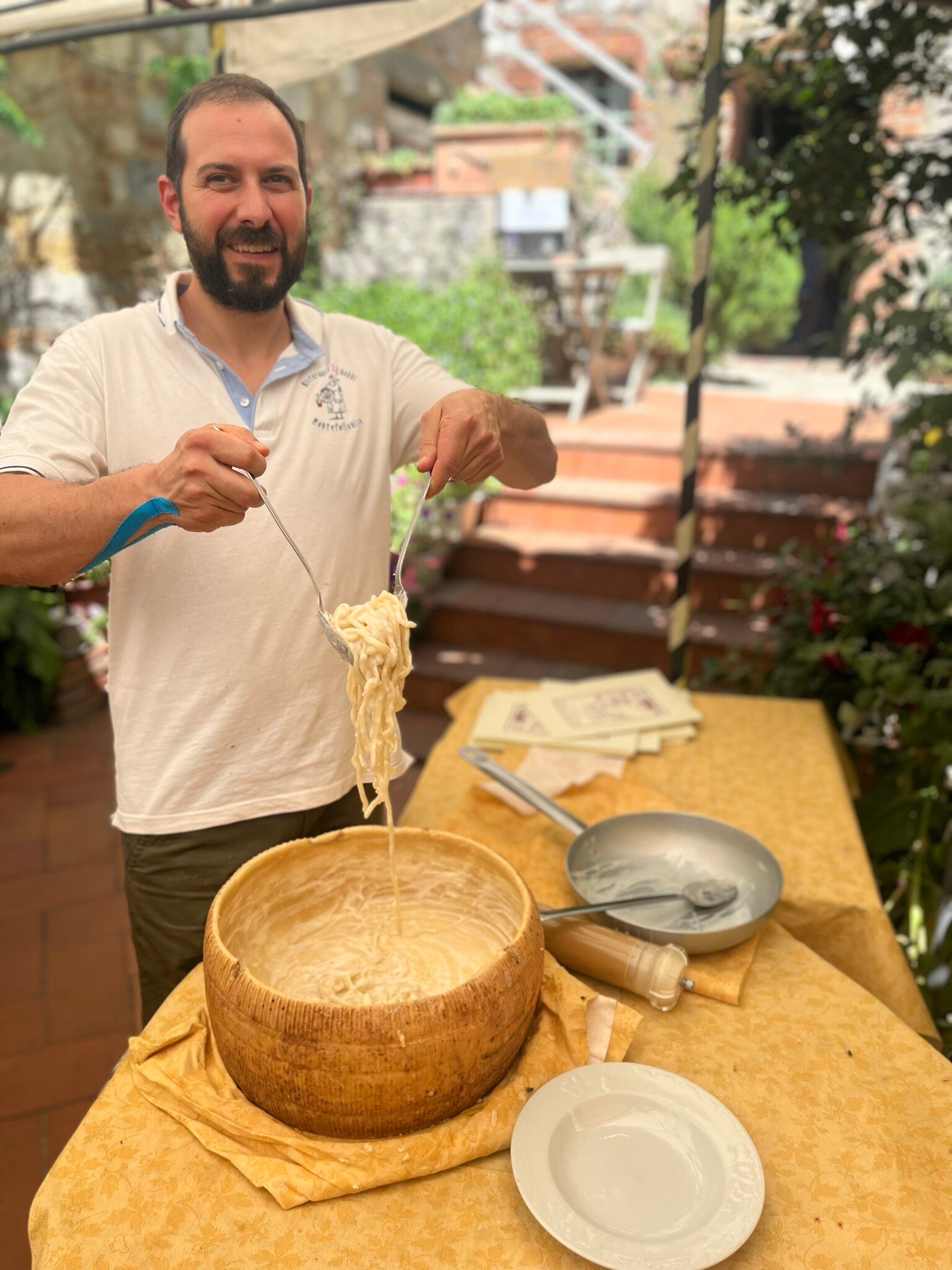 Matteo manteca le tagliatelle nella forma di pecorino, in terrazza